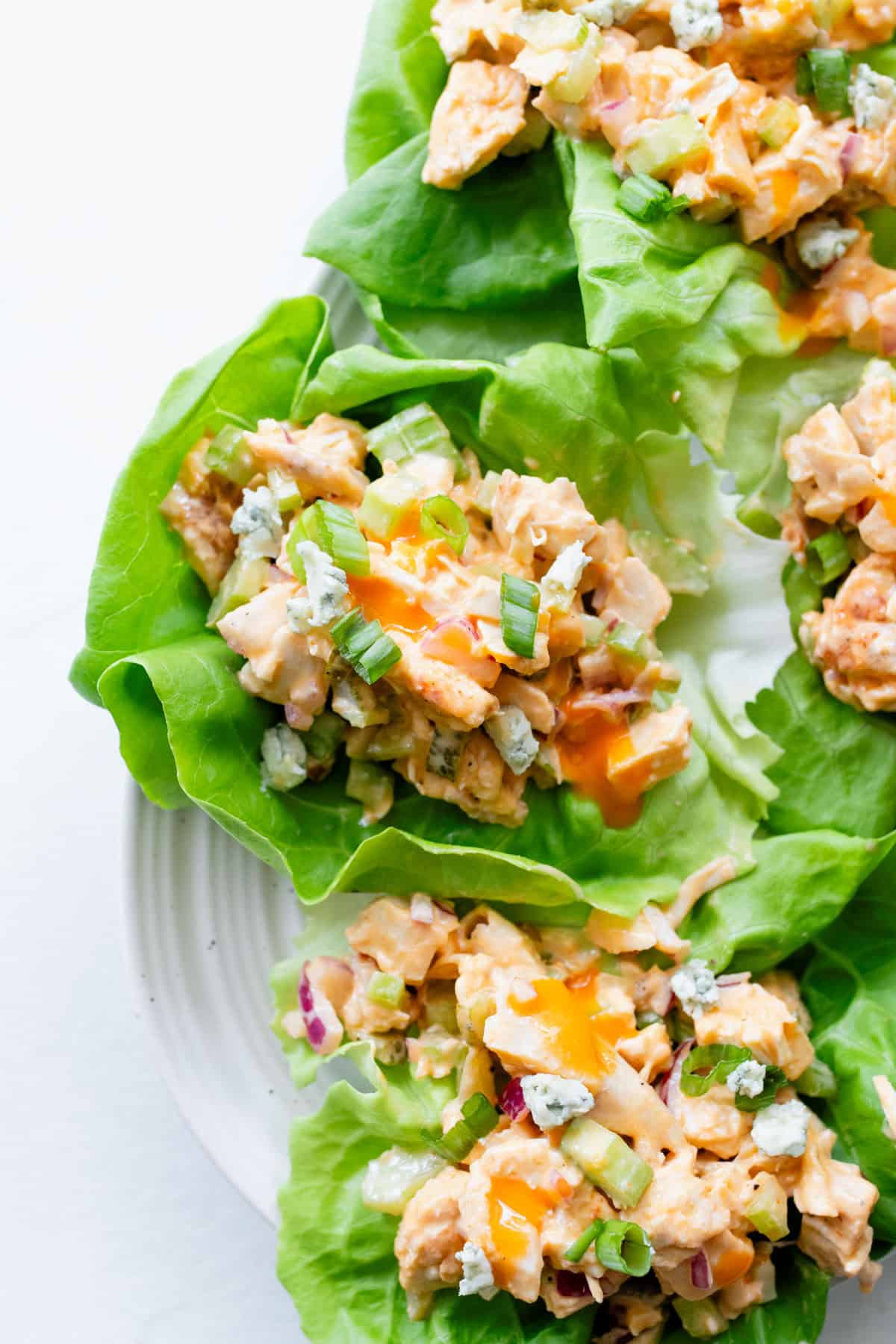 Lettuce cups with buffalo chicken salad in them on a serving platter.