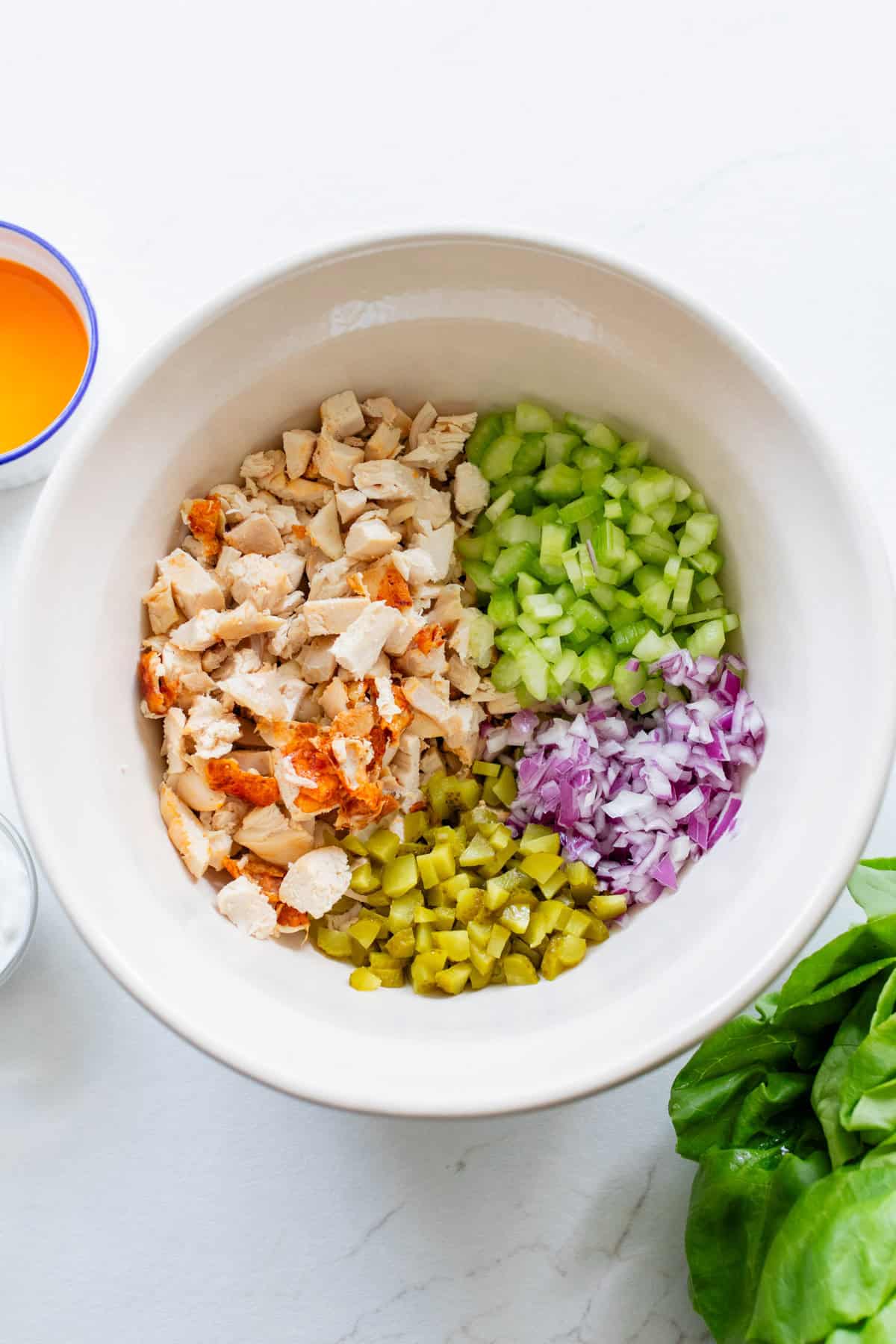 Ingredients for buffalo chicken salad separated out in a bowl.