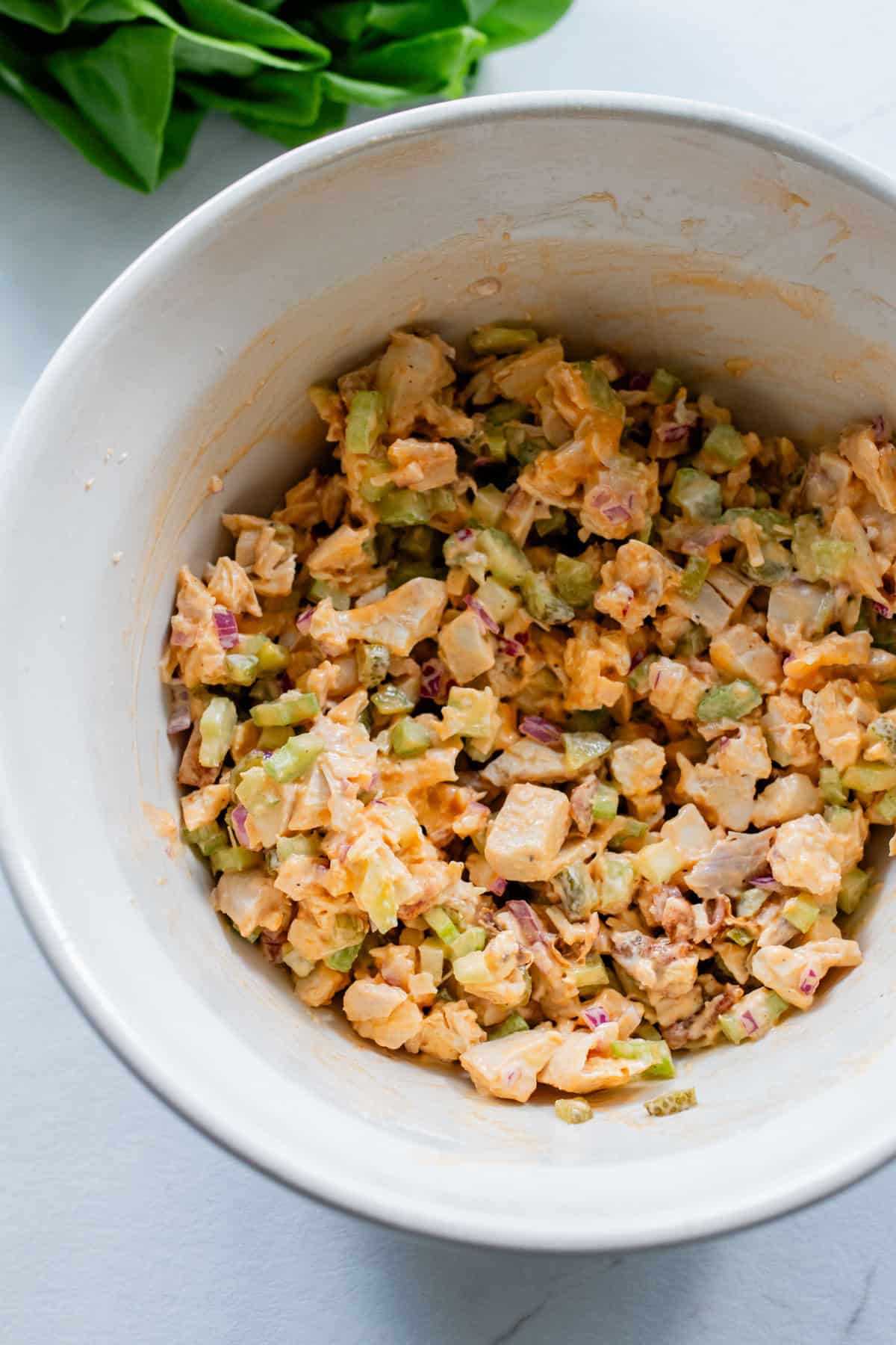A white bowl with buffalo chicken salad mixed together.
