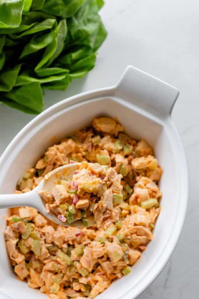 Buffalo chicken salad in a serving platter with a spoon scooping some out.