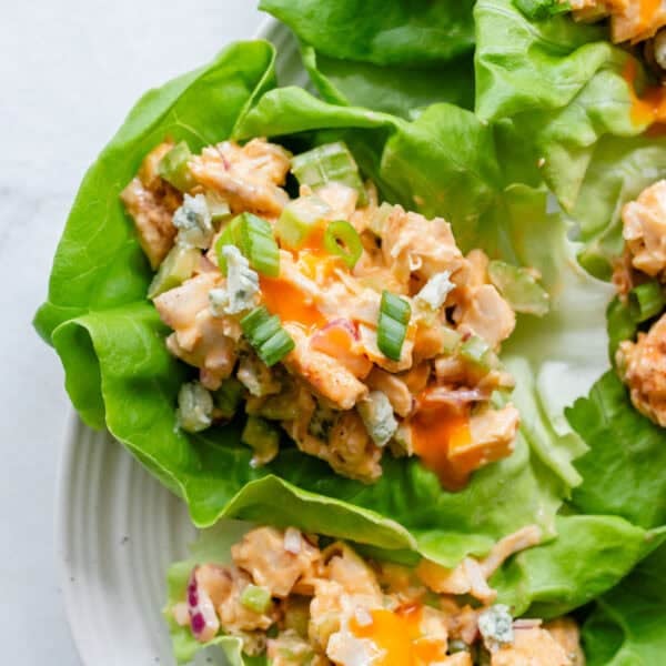Buffalo chicken salad in lettuce cups on a white platter.