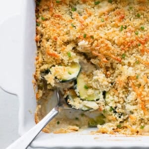 Part of a casserole dish of gratin with a silver serving spoon scooping some out.