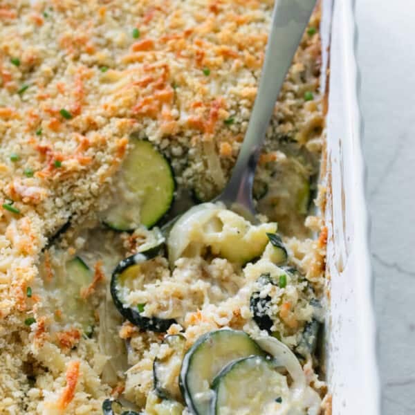 A casserole dish with zucchini gratin being scooped out.