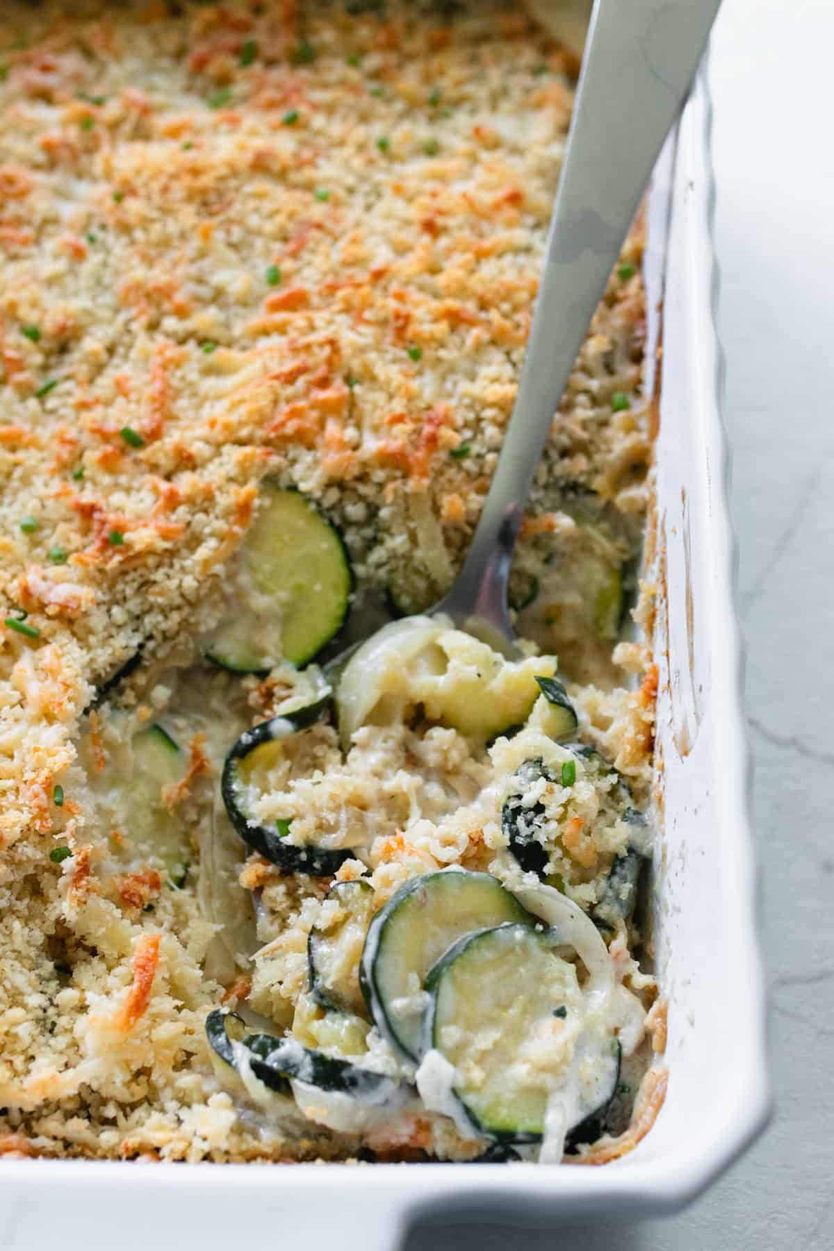 A casserole dish with zucchini gratin being scooped out.