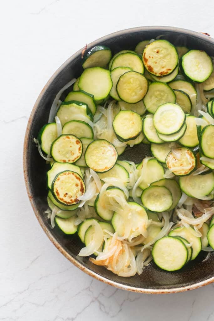 Zucchini cut into coins and onion in a skillet.