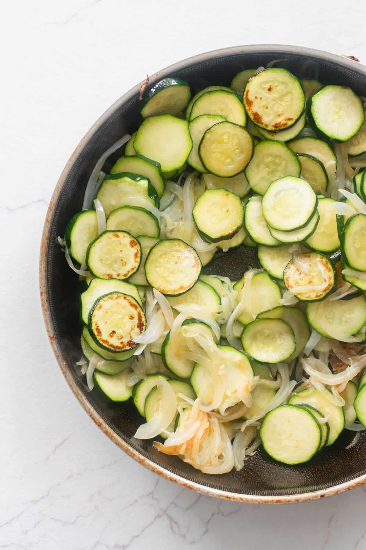 Zucchini cut into coins and onion in a skillet.