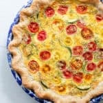 A quiche in a pie plate on a counter.