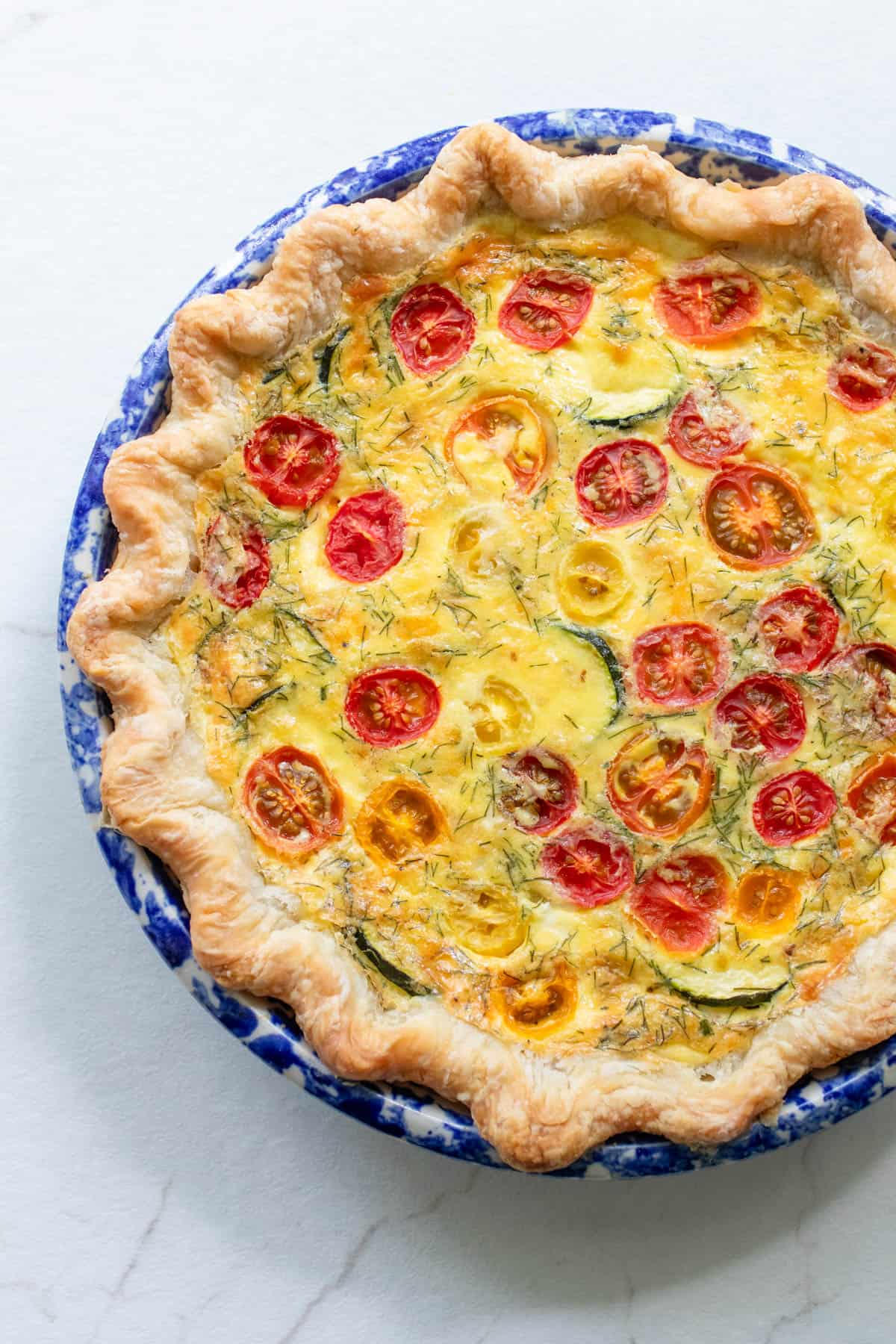 A quiche in a pie plate on a counter.
