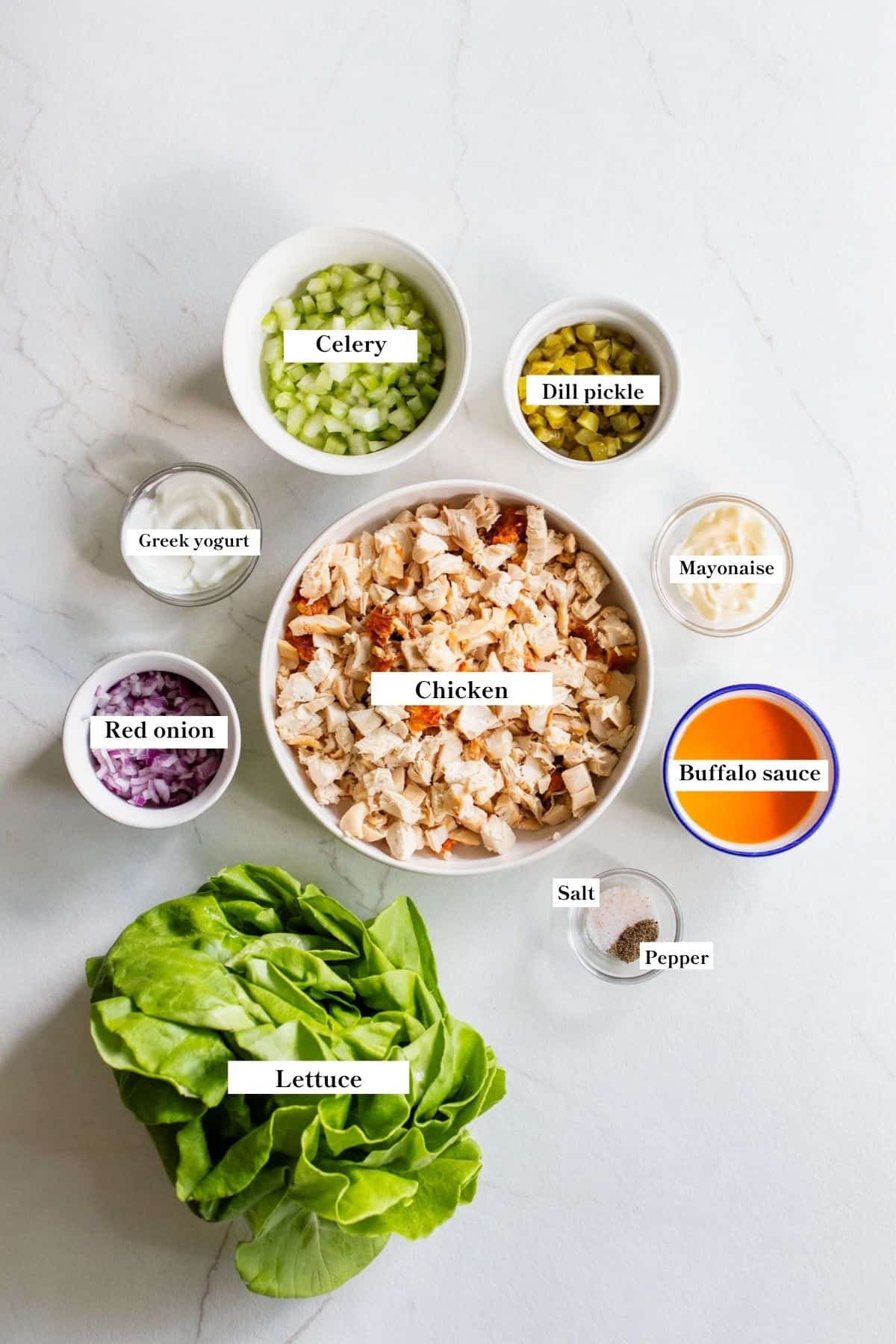 Ingredients for buffalo chicken salad in bowls on a counter top.