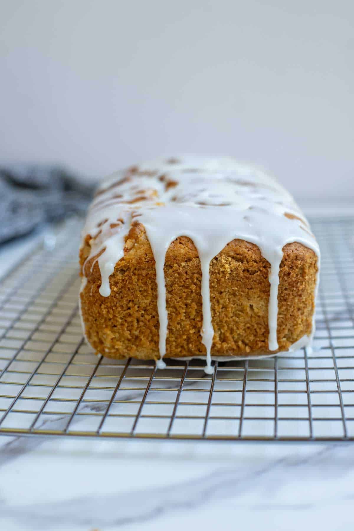 Powdered sugar glaze poured over a peach bread.