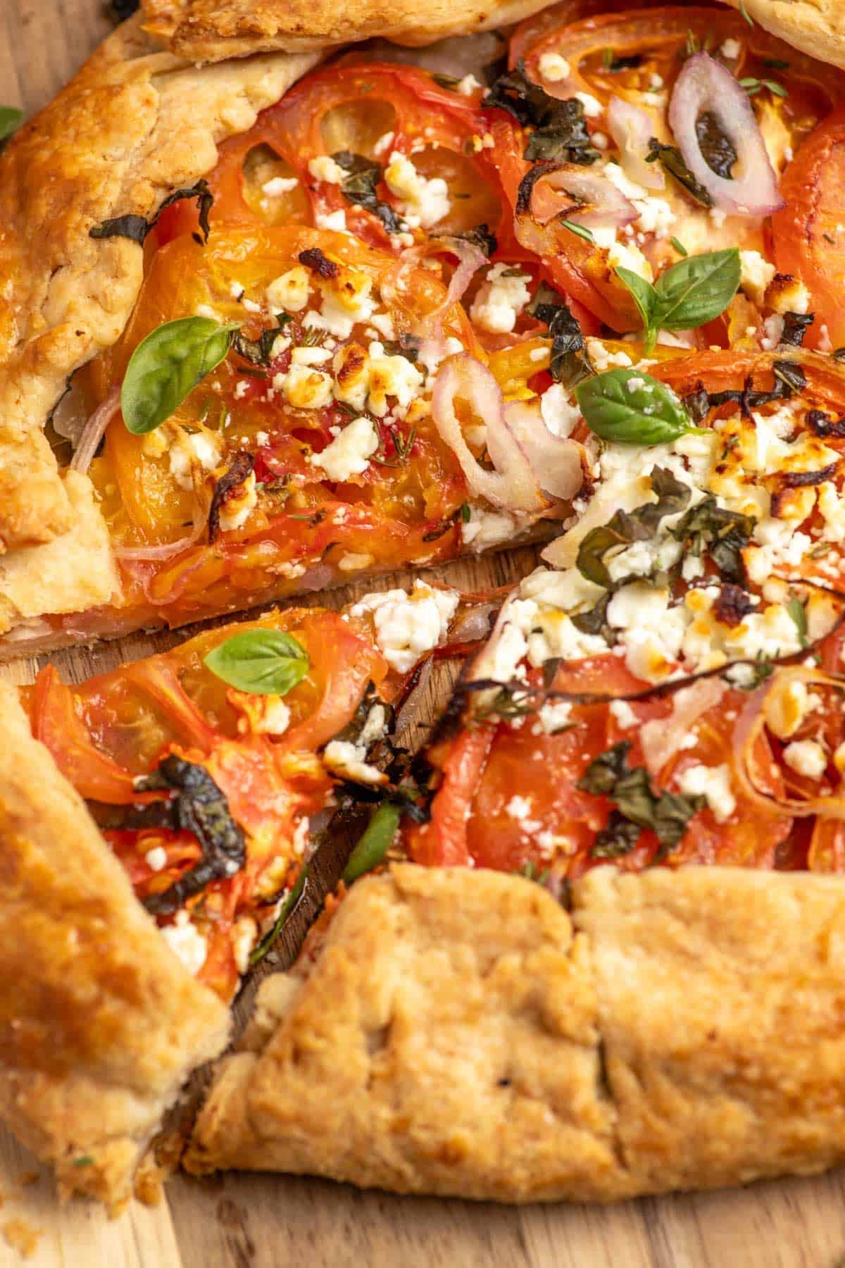 A slice of tomato galette cut from an entire tomato galette pie.