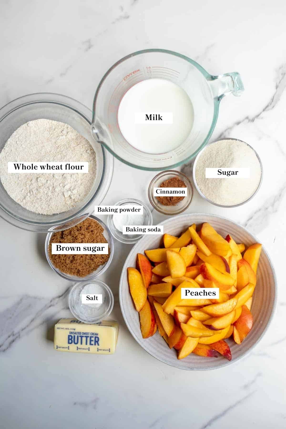 Ingredients for whole wheat peach cobbler in individual bowls on a countertop.