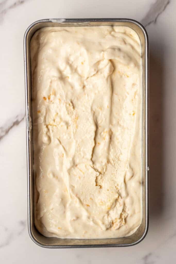 Peach ice cream added to a loaf pan to freeze.