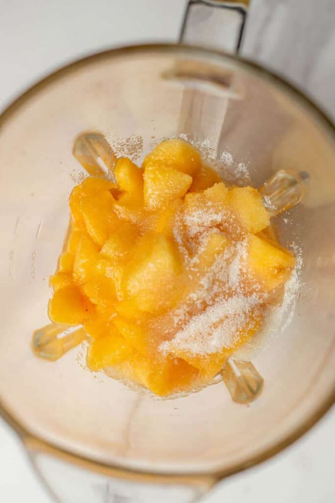 Peeled and chopped peaches in a blender covered with sugar.