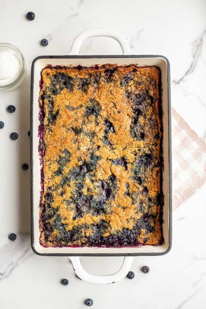 A golden brown blueberry cobbler in a 9 by 13 inch baking dish.