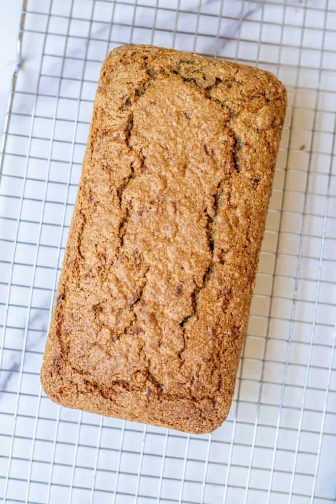 A baked loaf of zucchini bread on a wire rack.