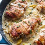 Chicken breasts in a cream sauce with peaches in a cast iron skillet.