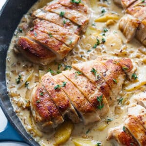 Chicken breasts in a cream sauce with peaches in a cast iron skillet.