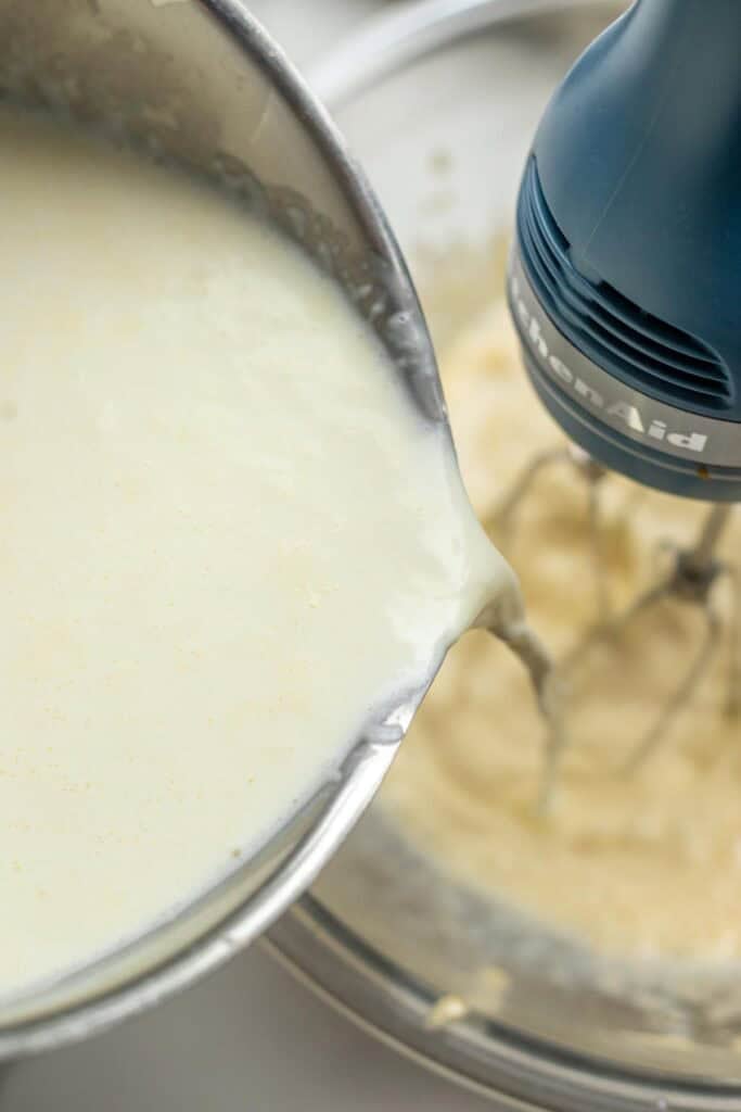 Milk in a saucepan poured into a bowl of a stand mixer.