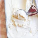 A loaf pan of ice cream with an ice cream scoop scooping some out.