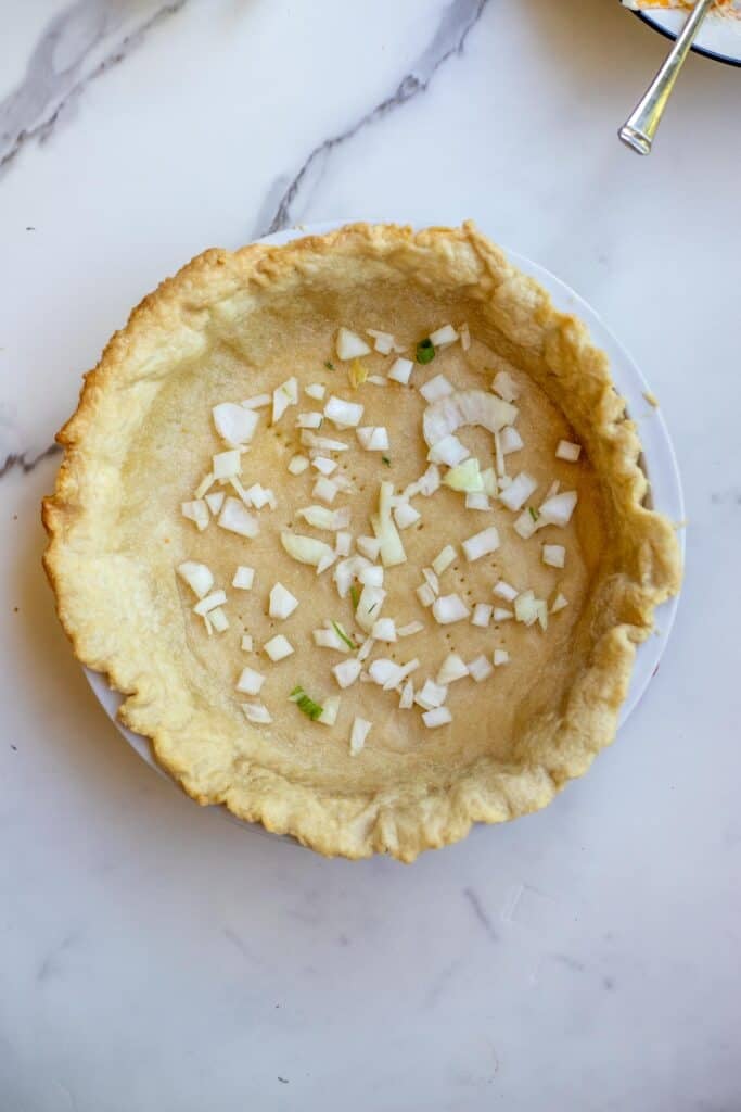 Diced onions added to a prebaked pie crust.
