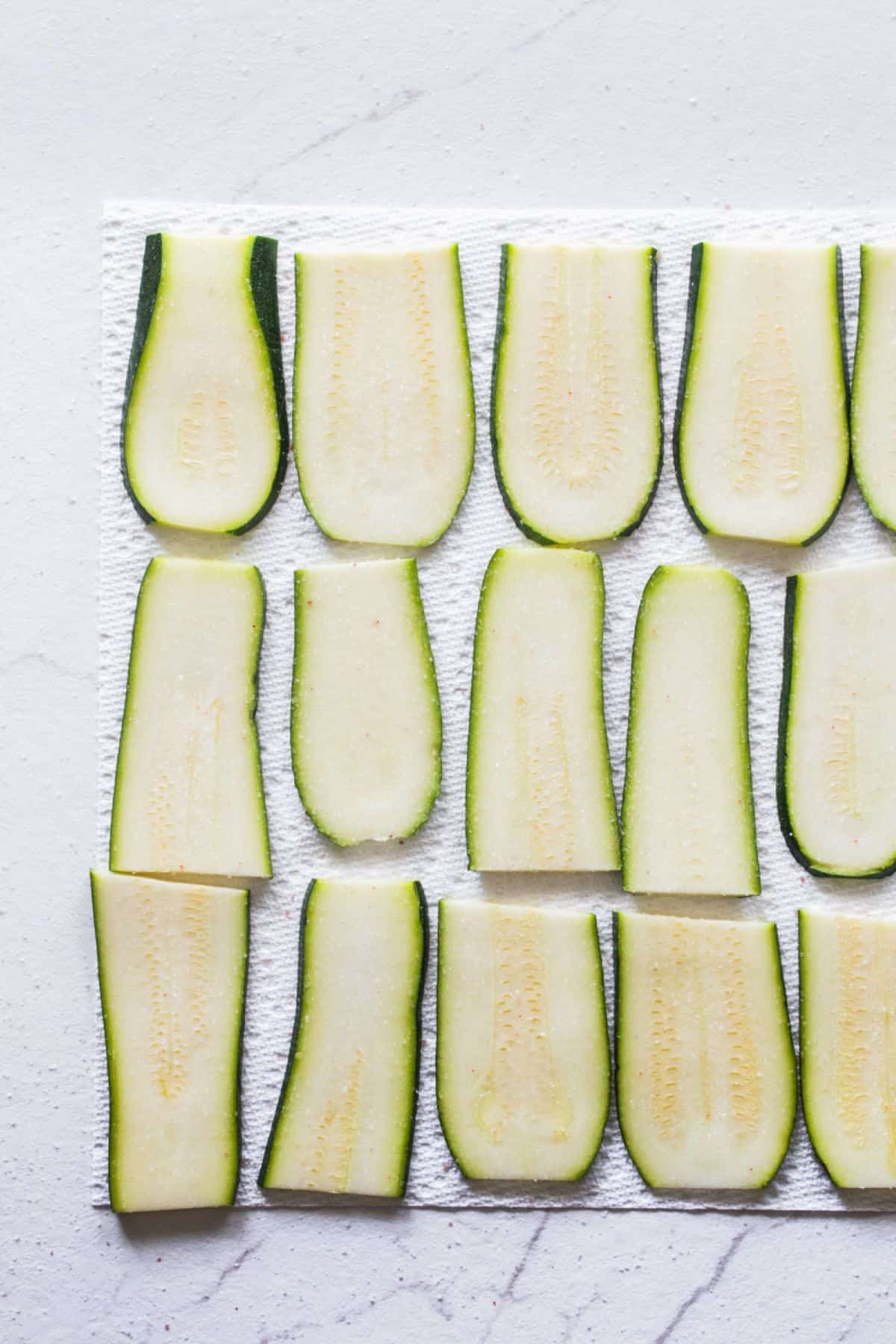 Thin slices of zucchini drying on paper towels.