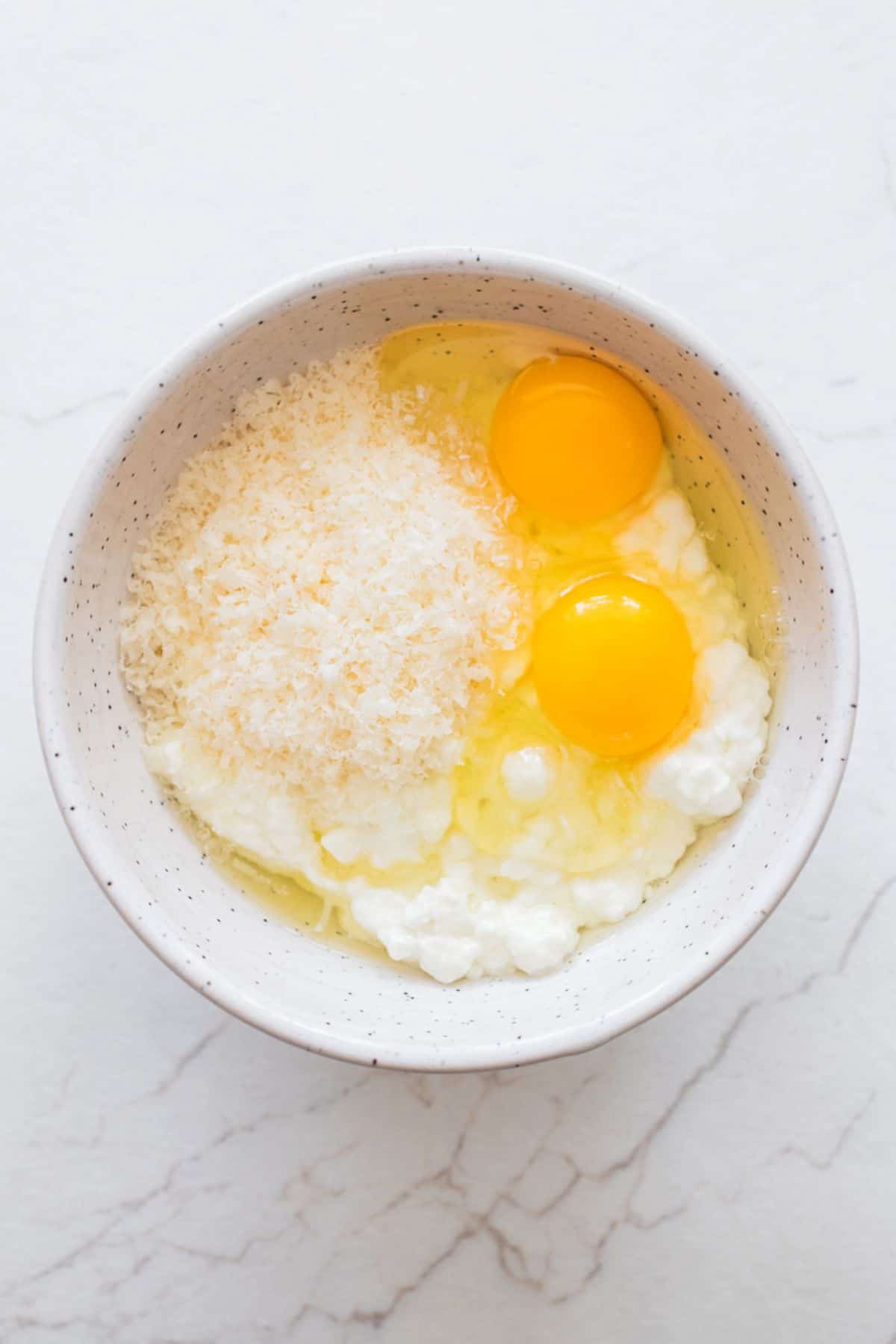 Eggs, cheese, and parmesan in a bowl.