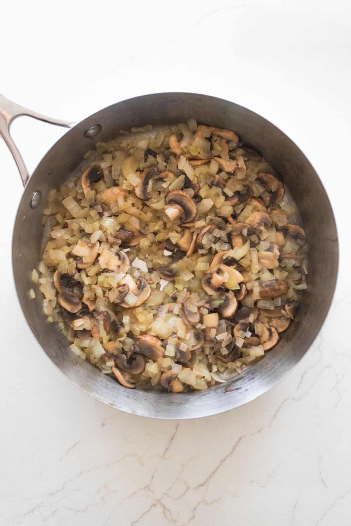 Onions and mushrooms sauteing in a pan.