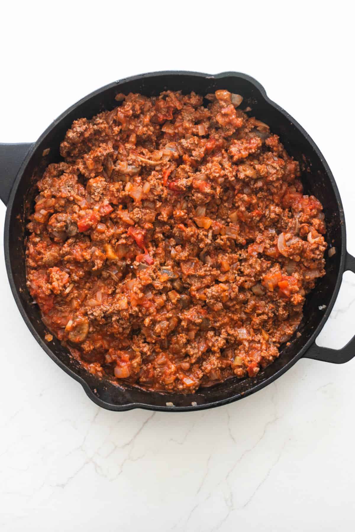 Meat, sautéed veggies, and sauce mixed together in a skillet.