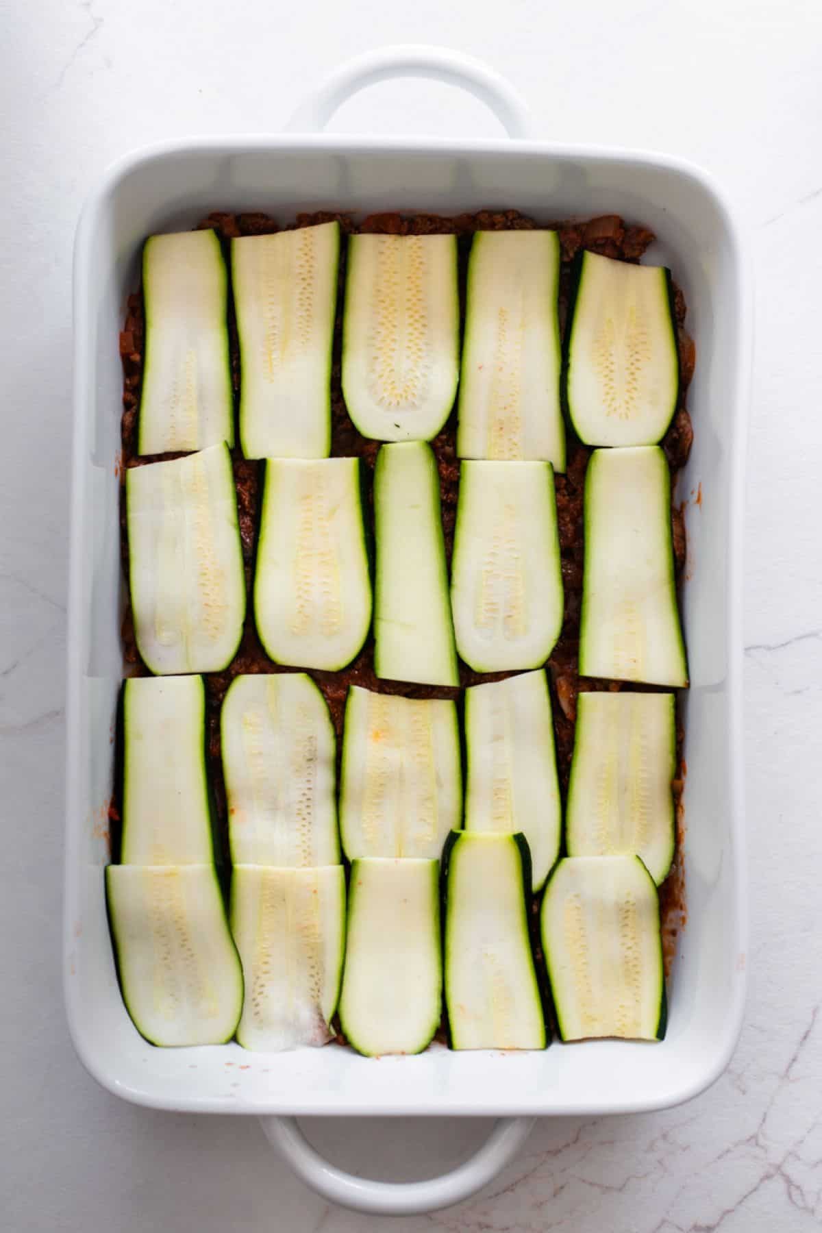 Slices of zucchini laid out in a casserole dish.