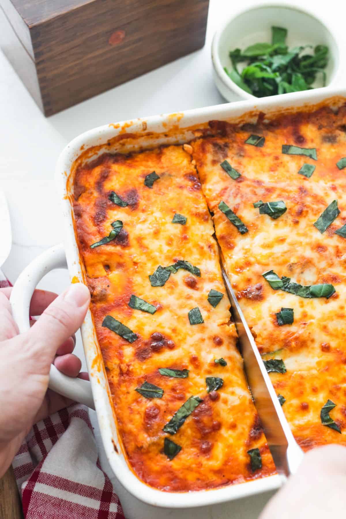 A baked zucchini lasagna being sliced into with a knife.