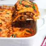 A slice of zucchini lasagna being lifted out of a casserole dish.