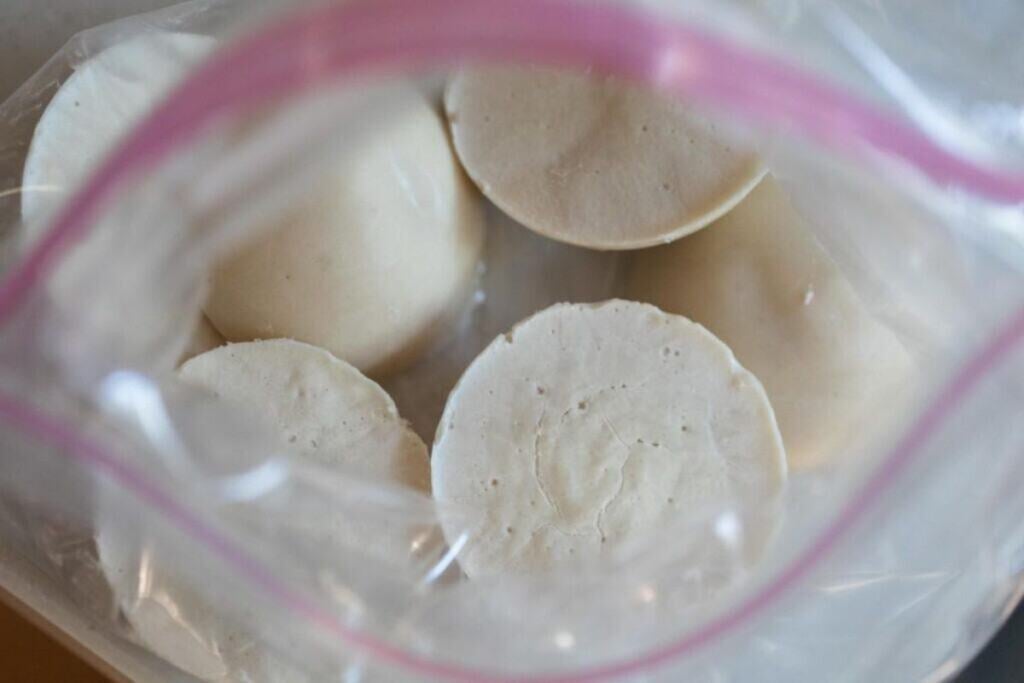 An opened freezer bag with frozen chunks of sourdough starter inside.