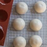 Frozen sourdough starter cups on a wire rack with a silicone mold next to it.