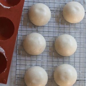 Frozen sourdough starter cups on a wire rack with a silicone mold next to it.