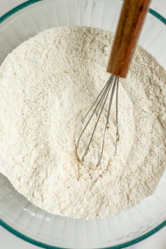 flour, salt, and baking powder mixed in a glass bowl with a whisk.