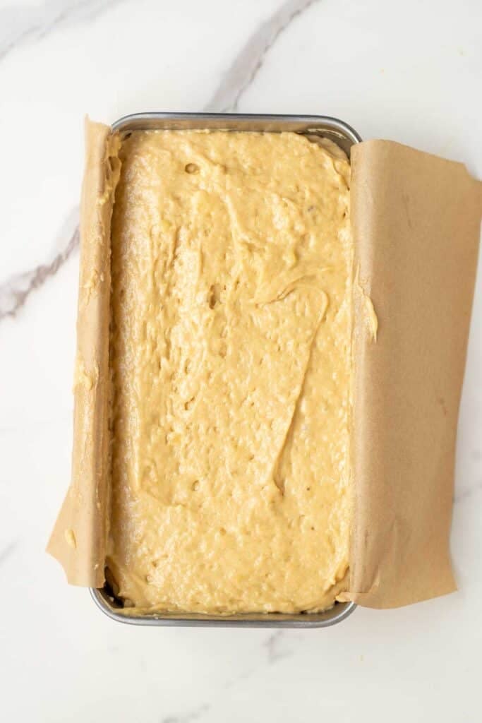 sourdough banana bread batter in a parchment paper lined loaf pan. 