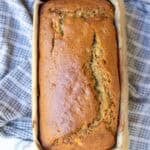 a fresh loaf of sourdough banana bread resting on a blue tea towel.