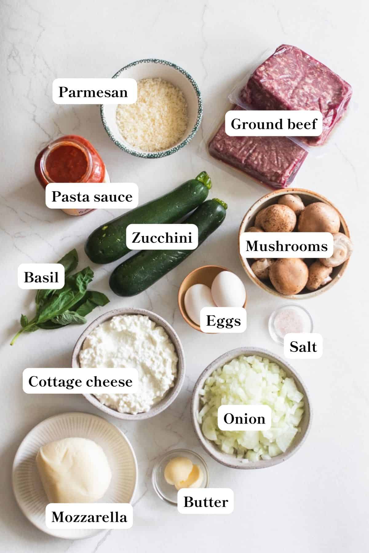 Ingredients for zucchini lasagna in bowls on a countertop.